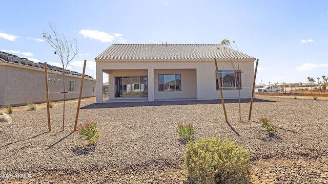 rear view of house with a tiled roof, fence, and stucco siding