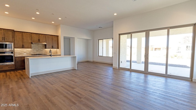 kitchen featuring tasteful backsplash, light countertops, recessed lighting, appliances with stainless steel finishes, and wood finished floors