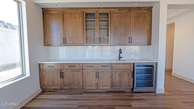 kitchen featuring backsplash, glass insert cabinets, dark wood-type flooring, wine cooler, and brown cabinetry