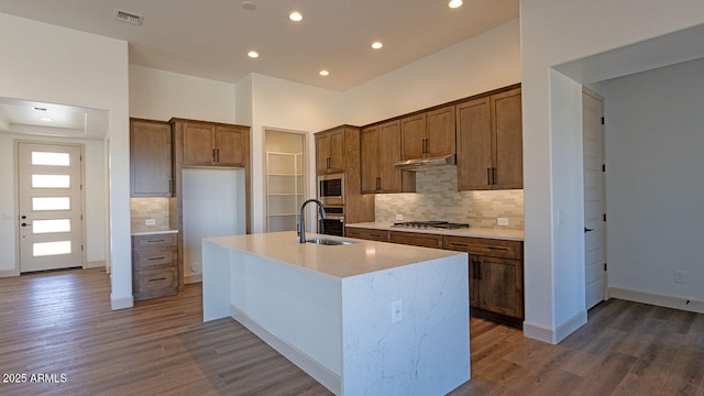 kitchen featuring dark wood-style floors, stainless steel appliances, under cabinet range hood, and a sink