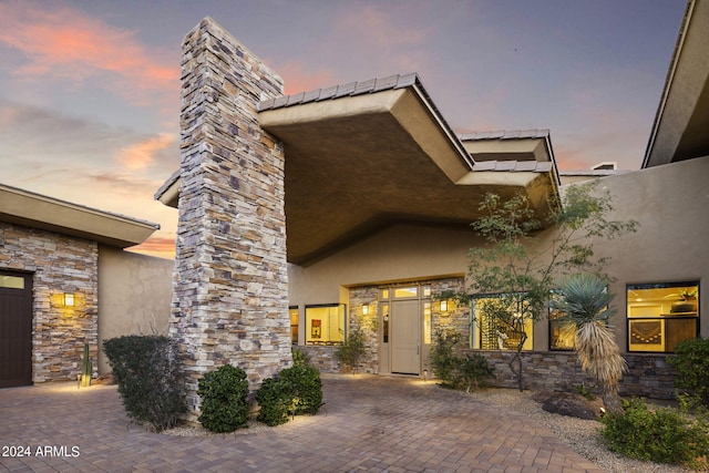 exterior entry at dusk featuring a patio