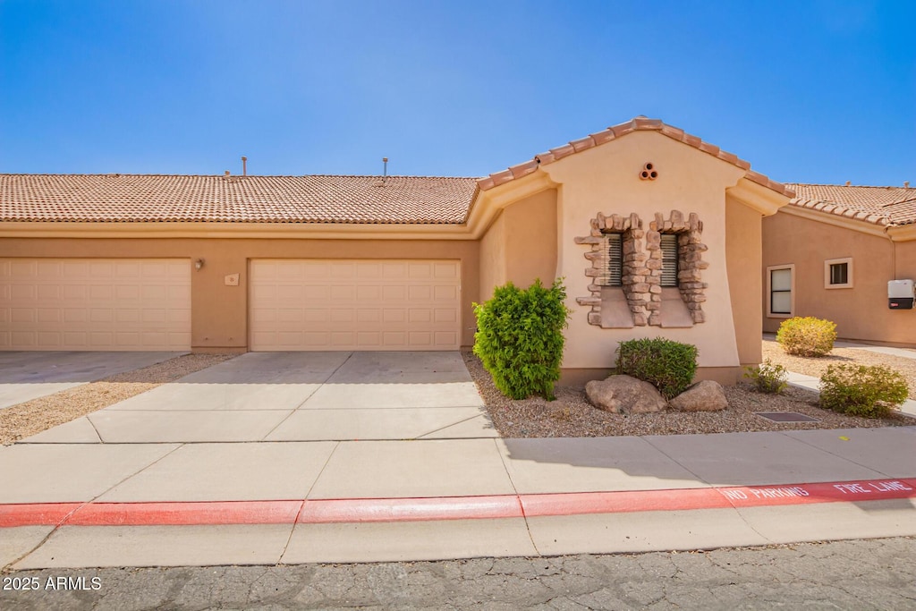 view of front of property with driveway, a tile roof, a garage, and stucco siding