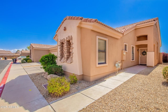 view of front of property with a tile roof, a gate, and stucco siding