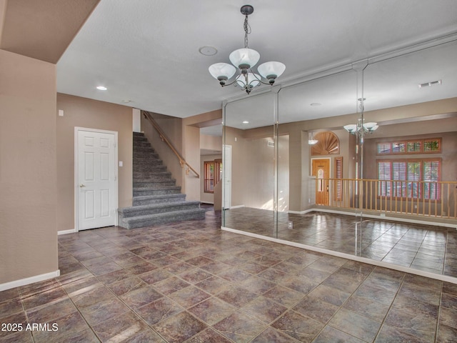 unfurnished room with an inviting chandelier, baseboards, stairway, and visible vents