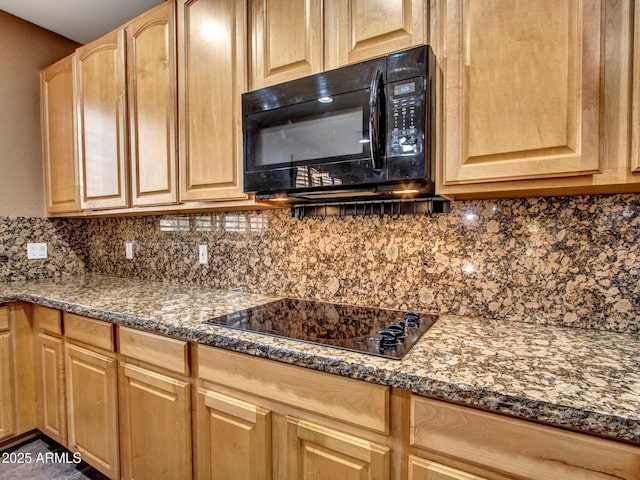 kitchen with light brown cabinets, dark stone countertops, black appliances, and tasteful backsplash
