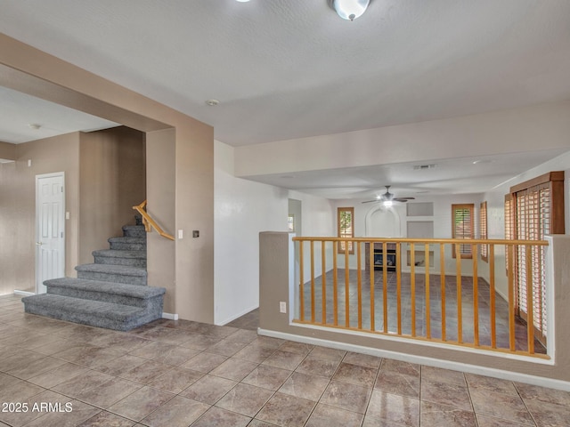 empty room with visible vents, baseboards, stairway, and ceiling fan