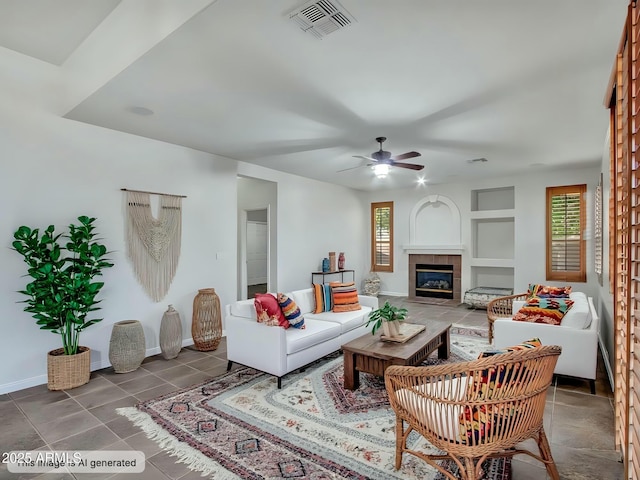 living room featuring visible vents, baseboards, a tiled fireplace, a ceiling fan, and tile patterned flooring