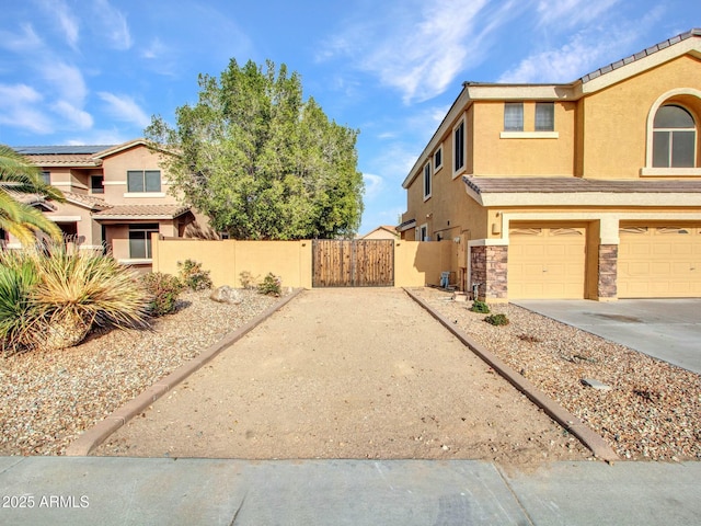 exterior space featuring a gate, fence, an attached garage, concrete driveway, and stucco siding