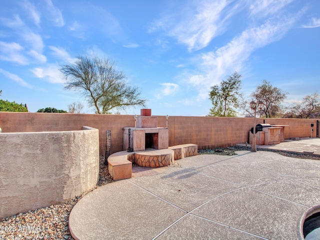 view of patio with a fenced backyard and an outdoor fireplace