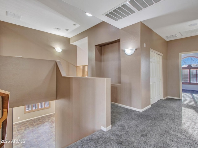 hallway featuring baseboards, carpet floors, and visible vents