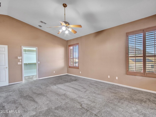 spare room with carpet flooring, lofted ceiling, baseboards, visible vents, and ceiling fan