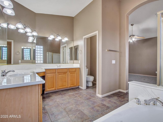 full bathroom featuring double vanity, toilet, a sink, and a garden tub