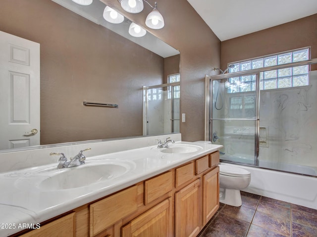full bath featuring double vanity, a sink, toilet, and shower / bath combination with glass door