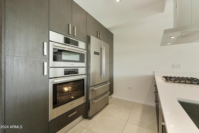7120 E Kierland Blvd Unit 316, Scottsdale, AZ 85254 - kitchen featuring stainless steel appliances, wall chimney range hood, light tile patterned floors, baseboards, and light countertops