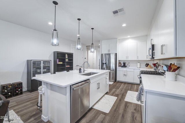 kitchen with a center island with sink, visible vents, appliances with stainless steel finishes, light countertops, and a sink