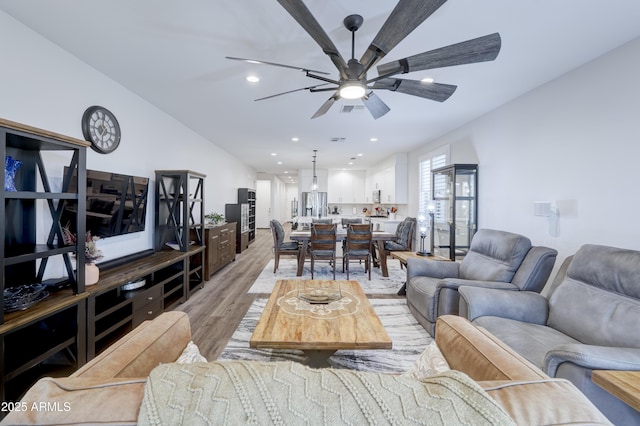 living room with ceiling fan, lofted ceiling, light wood-style flooring, recessed lighting, and visible vents