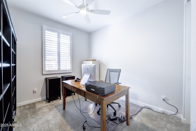 carpeted office space with a ceiling fan and baseboards