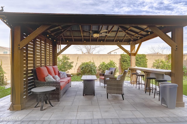 view of patio featuring outdoor dry bar, a gazebo, a fenced backyard, and an outdoor living space