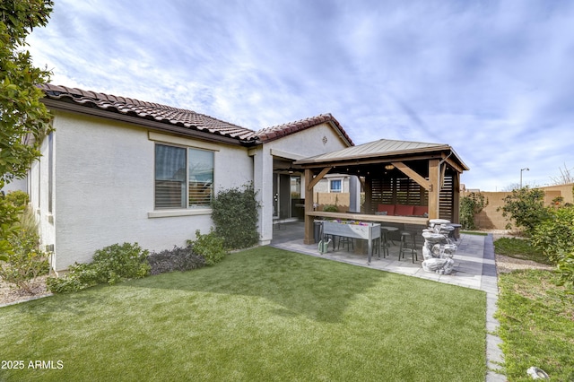 rear view of property featuring stucco siding, a fenced backyard, a patio area, and a gazebo