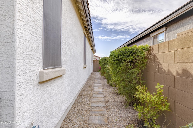 view of side of property featuring fence and stucco siding