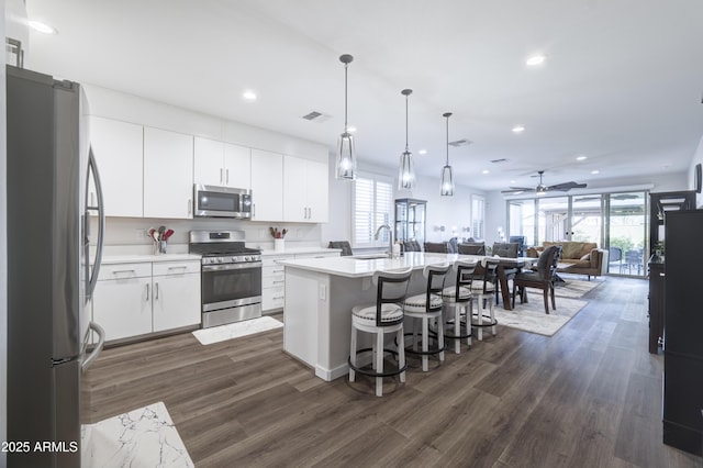 kitchen featuring visible vents, appliances with stainless steel finishes, open floor plan, a kitchen breakfast bar, and a sink