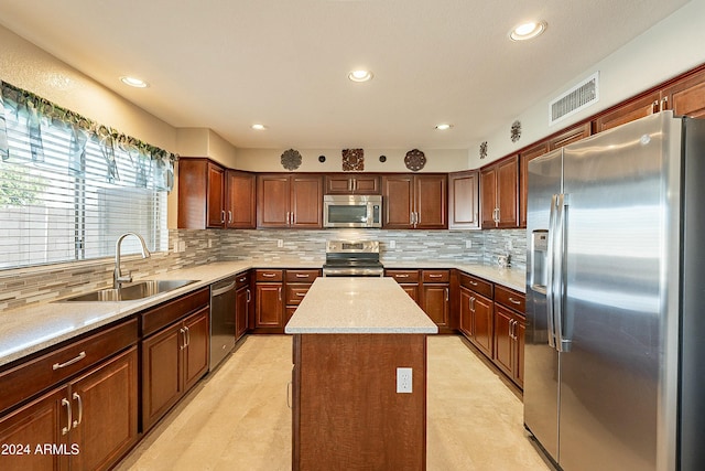 kitchen featuring sink, a center island, light stone counters, decorative backsplash, and appliances with stainless steel finishes