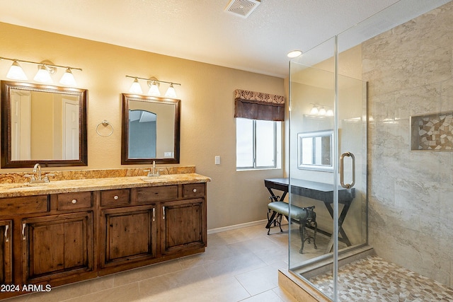 bathroom with tile patterned floors, vanity, a textured ceiling, and walk in shower