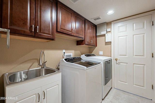 clothes washing area with cabinets, sink, and washing machine and clothes dryer