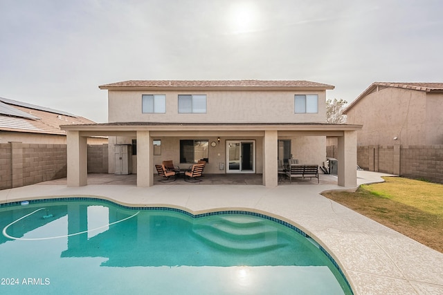 rear view of house with outdoor lounge area, a patio, and a fenced in pool