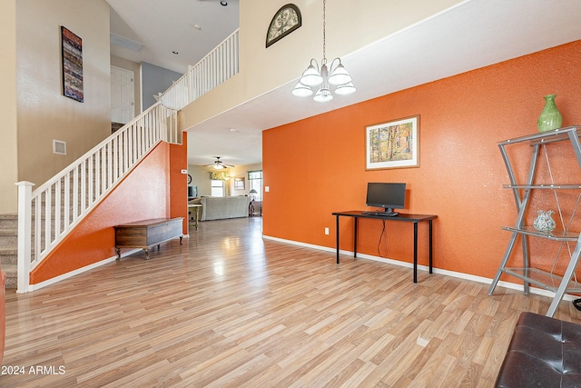 interior space featuring a high ceiling, light hardwood / wood-style floors, and ceiling fan with notable chandelier