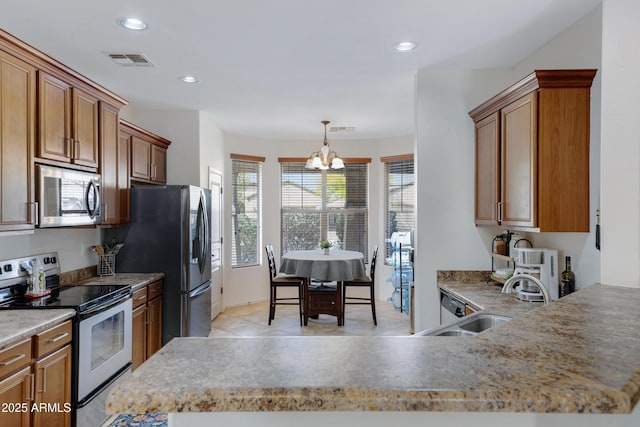 kitchen featuring visible vents, brown cabinets, stainless steel appliances, a sink, and recessed lighting