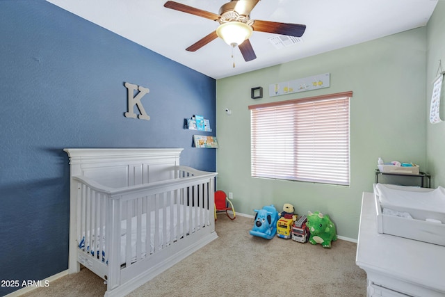 carpeted bedroom featuring visible vents, ceiling fan, a crib, and baseboards