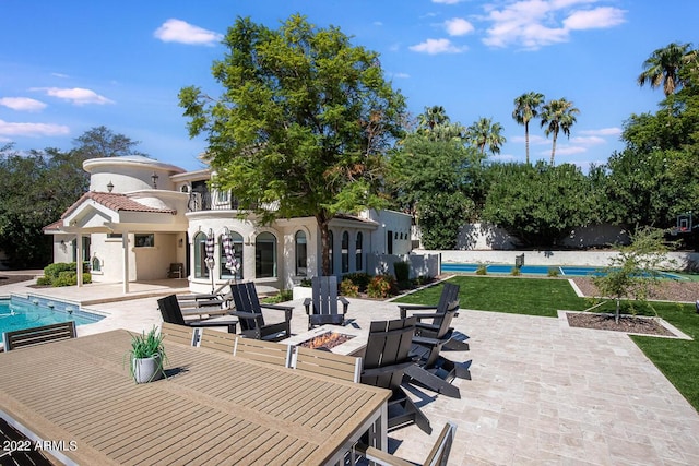 view of patio / terrace with an outdoor fire pit, a balcony, and an outdoor pool