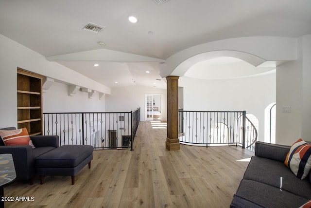 hallway featuring lofted ceiling, recessed lighting, visible vents, light wood-style floors, and ornate columns