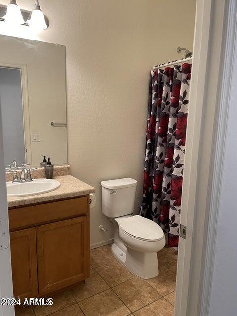 bathroom featuring tile patterned floors, curtained shower, vanity, and toilet