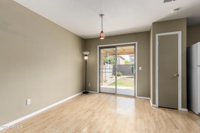 unfurnished dining area featuring visible vents, light wood finished floors, and baseboards