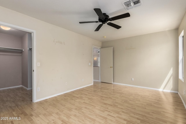 unfurnished bedroom with light wood-type flooring, baseboards, visible vents, and a walk in closet