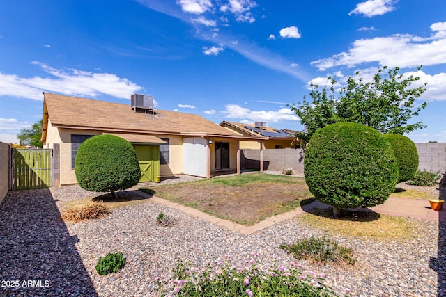 rear view of house featuring a gate, central AC, a storage shed, a fenced backyard, and stucco siding
