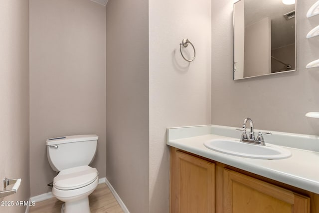 bathroom with wood finished floors, vanity, baseboards, toilet, and visible vents