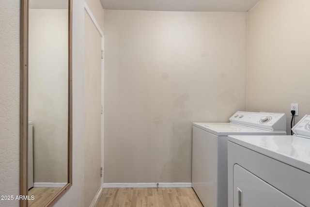 laundry area featuring washing machine and dryer, light wood finished floors, baseboards, and laundry area