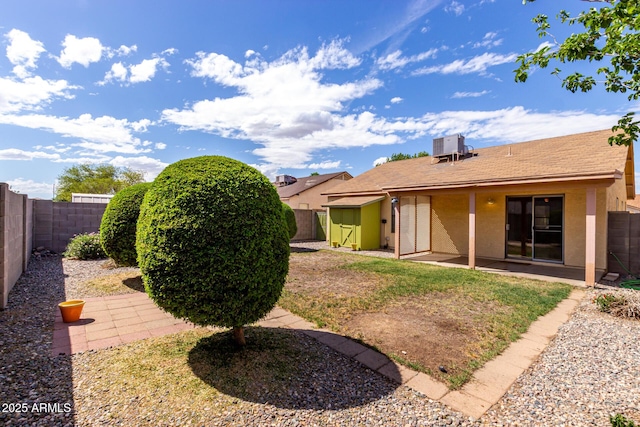 rear view of house with a patio, a fenced backyard, central AC, and stucco siding