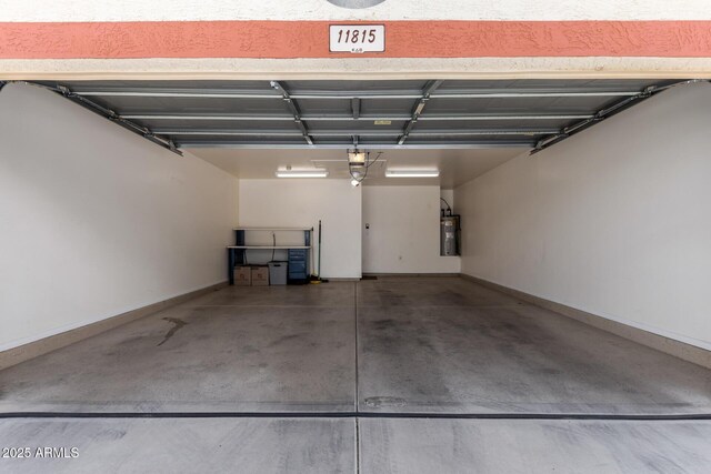 garage featuring baseboards, water heater, and a garage door opener