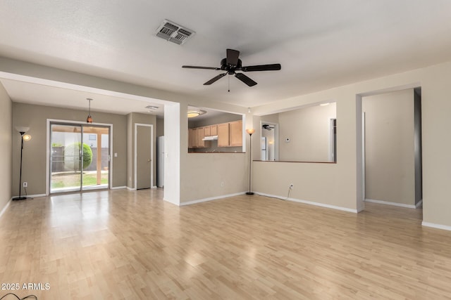 unfurnished living room featuring light wood-type flooring, visible vents, a ceiling fan, and baseboards