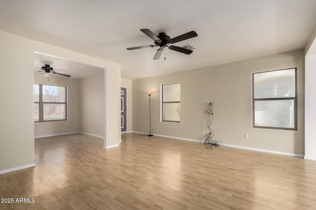 spare room with baseboards, a ceiling fan, light wood-style floors, and visible vents