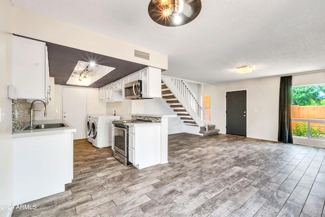 kitchen featuring visible vents, a sink, separate washer and dryer, stainless steel appliances, and white cabinets