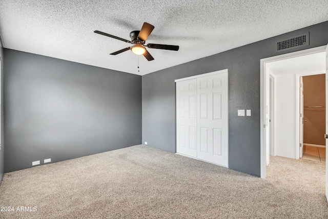 unfurnished bedroom featuring visible vents, carpet, ceiling fan, a textured ceiling, and a closet