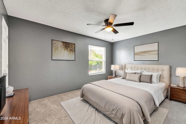 bedroom with light carpet, a ceiling fan, and a textured ceiling