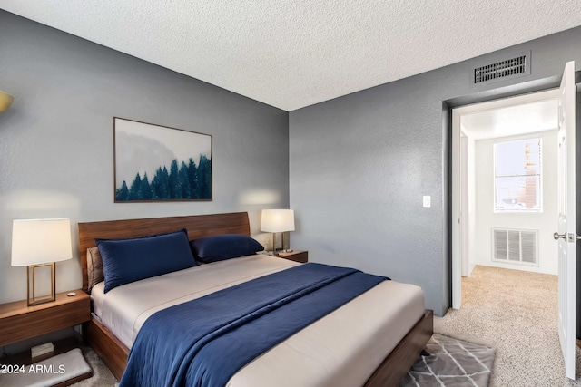 bedroom with a textured wall, visible vents, carpet, and a textured ceiling