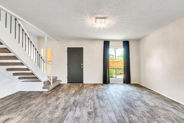 entrance foyer with stairway, a textured ceiling, and wood finished floors