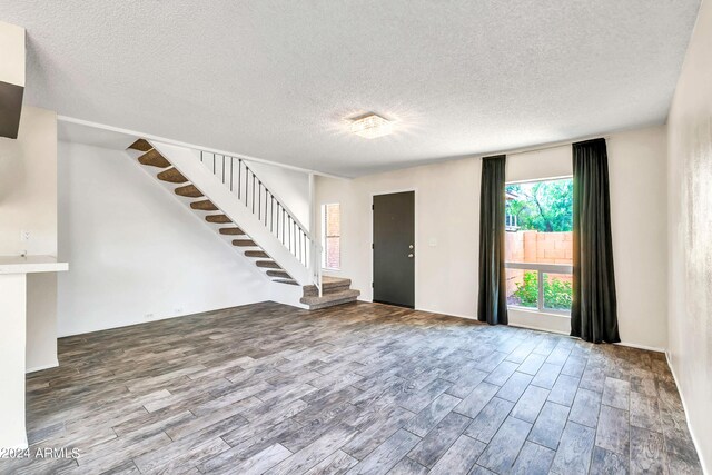 foyer featuring stairway, light wood finished floors, and a textured ceiling